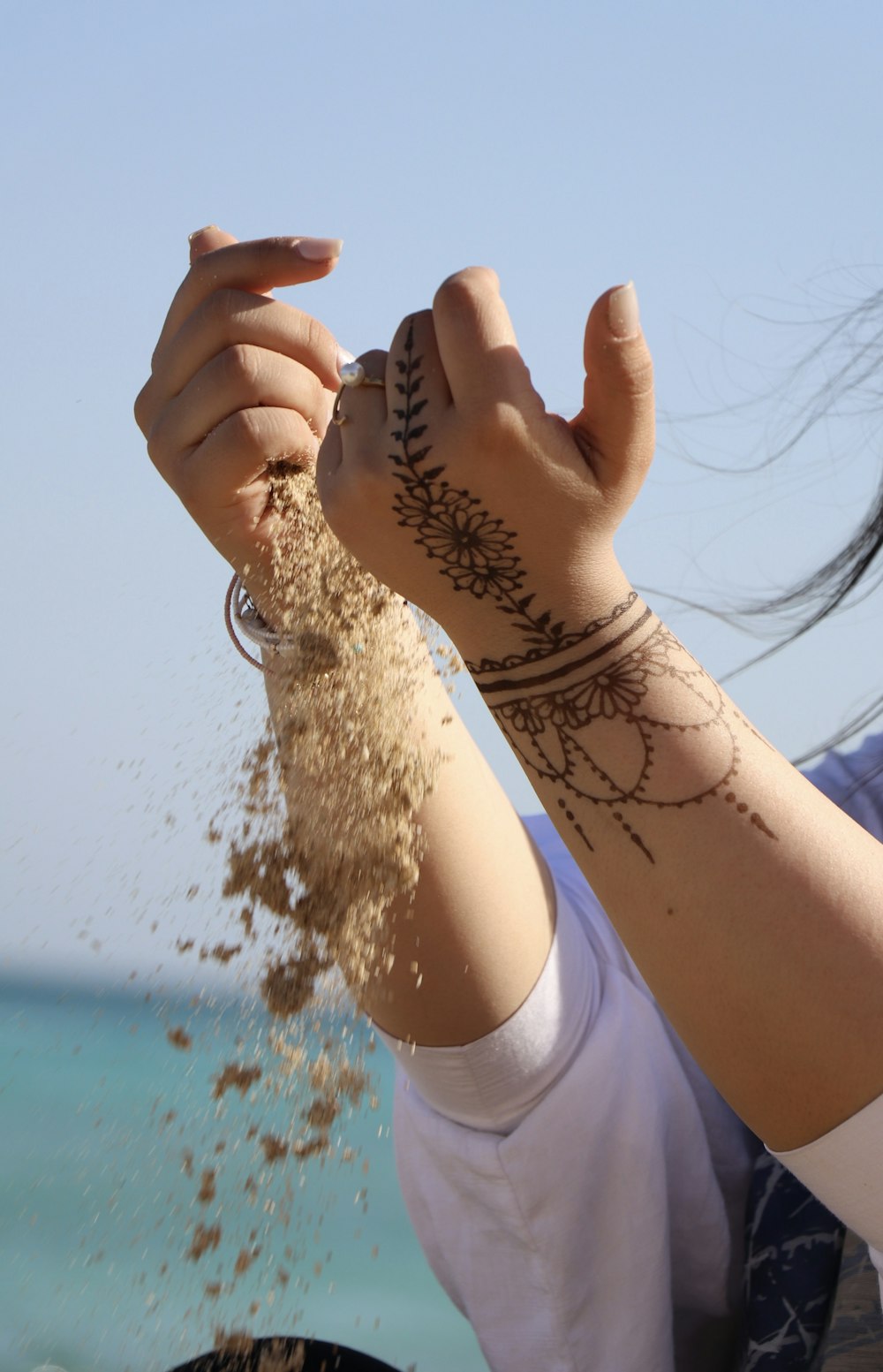 a woman with a tattoo on her arm throwing sand into the air