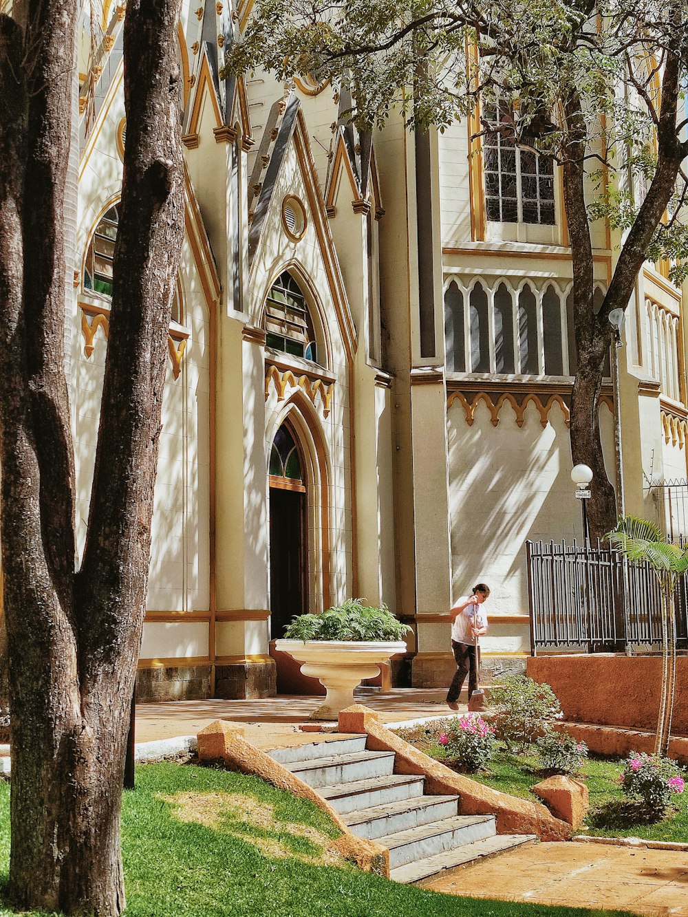 a man standing in front of a church next to a tree