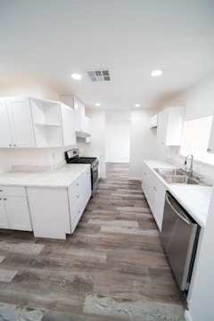 a kitchen with white cabinets and wood floors