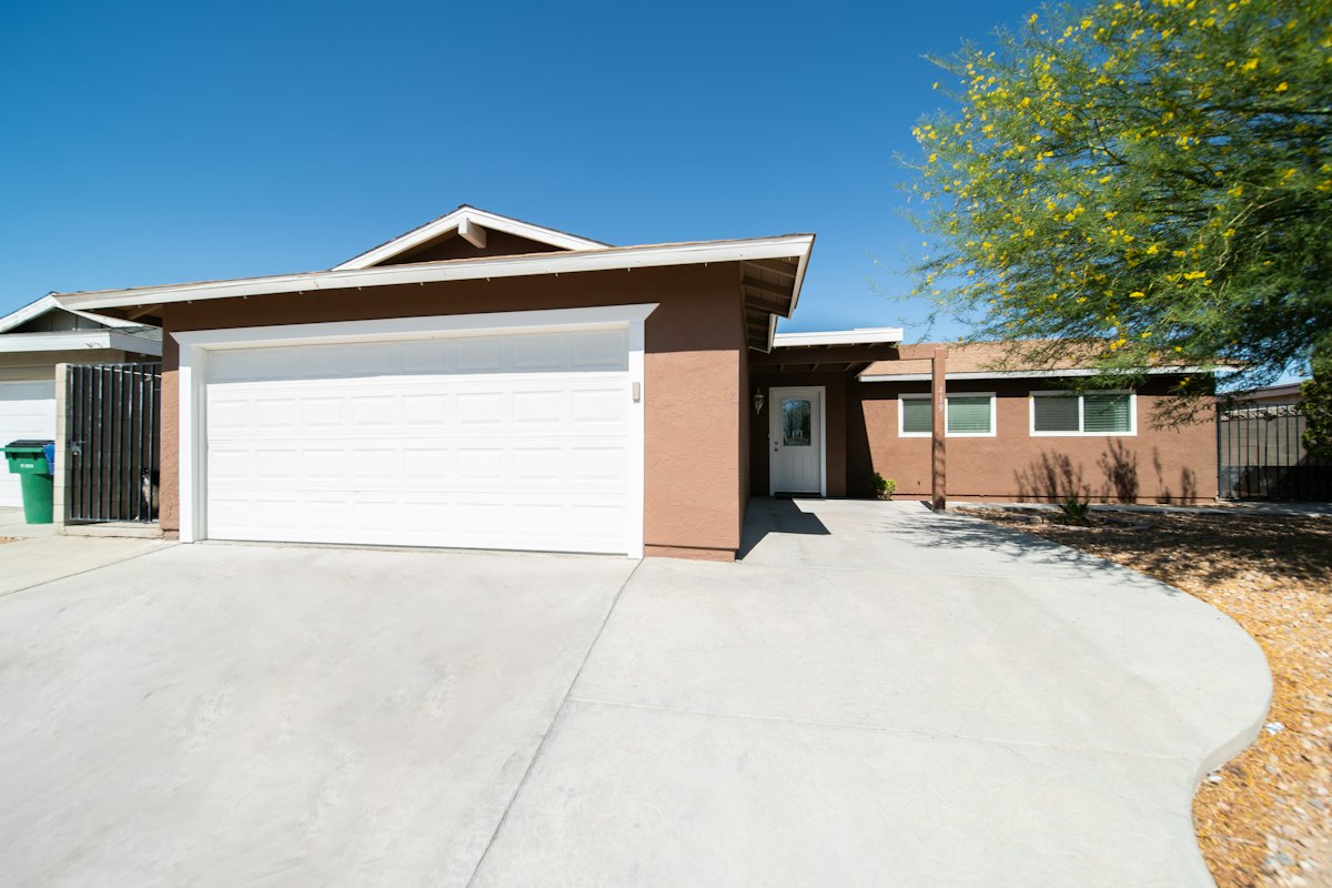 A stucco home with a two-car garage and a wide concrete driveway
