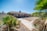 A technician in uniform inspecting a desert home's exterior for pests under bright Arizona sunlight.