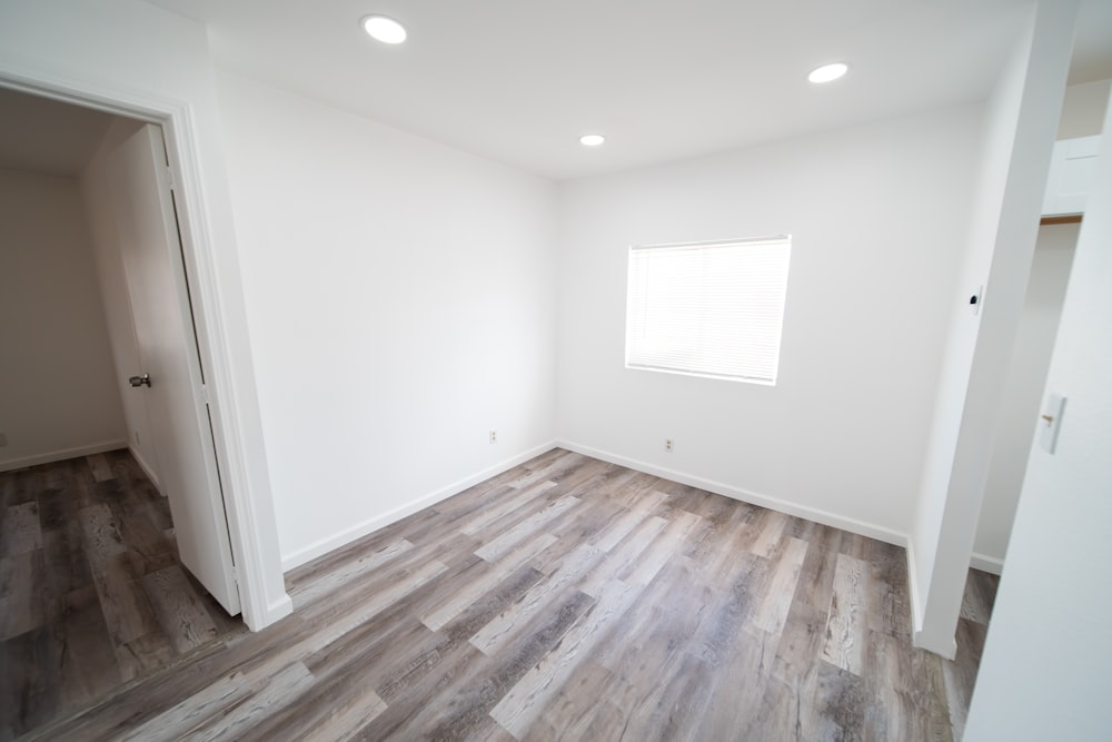 an empty room with white walls and wood floors