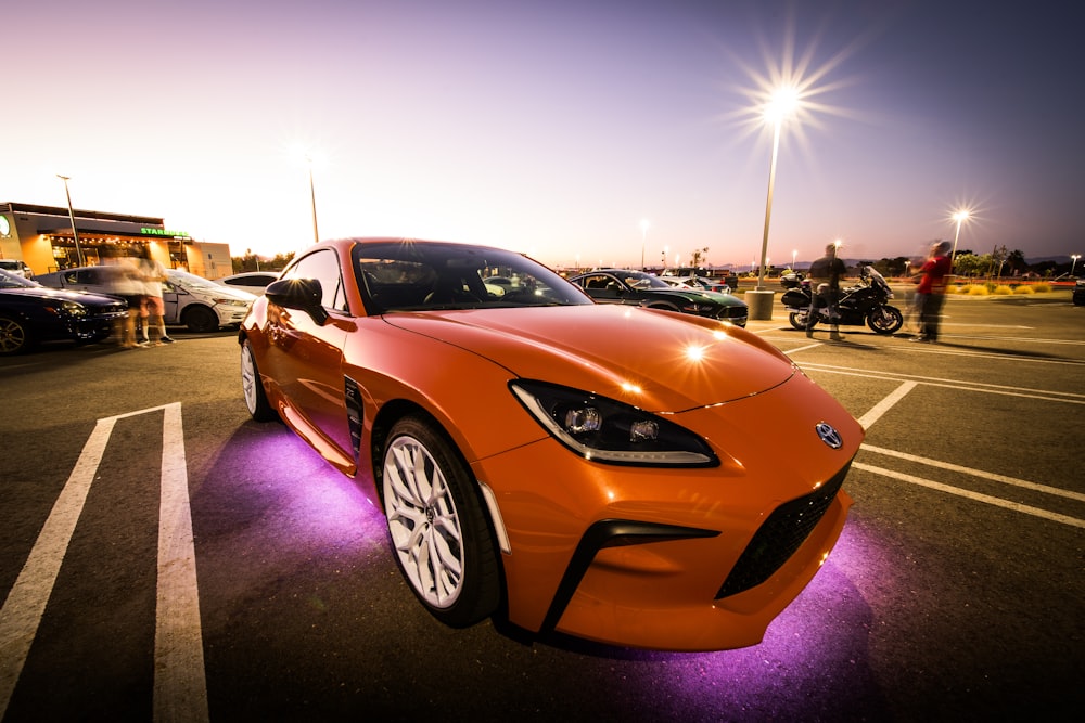 an orange sports car parked in a parking lot