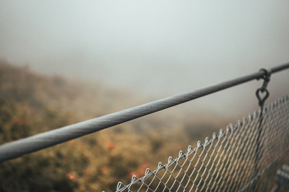 a close up of a chain link fence on a foggy day