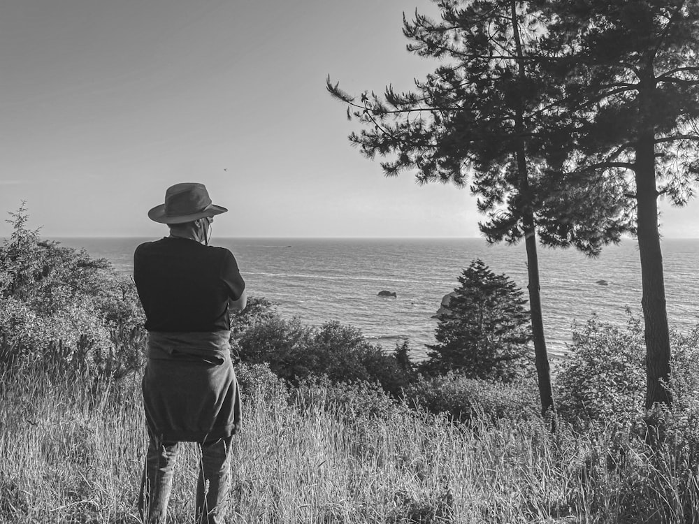 a person standing in a field looking at the ocean