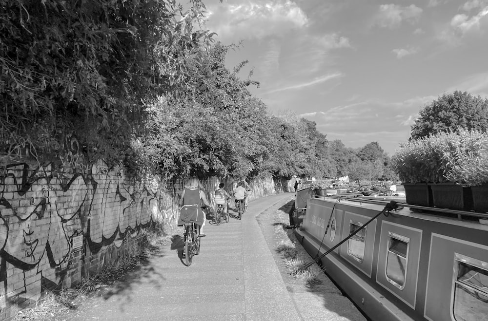 a black and white photo of people riding bikes on a path