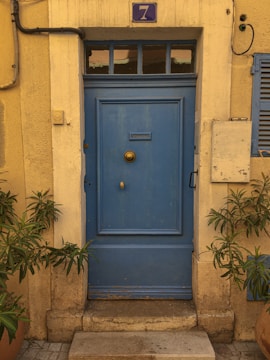 An inviting blue door with vintage hardware and a small window.
