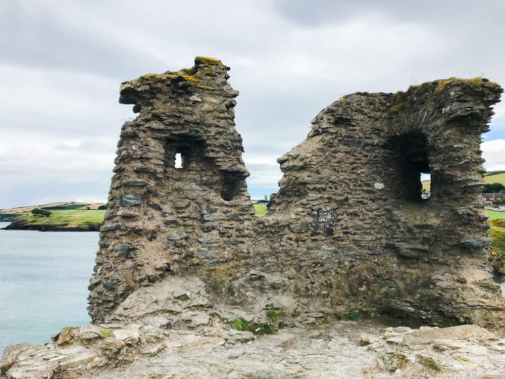 an old stone building sitting on top of a cliff next to a body of water