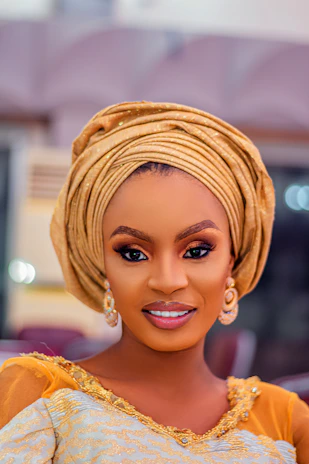 Elegant woman wearing a chic head wrap and matching accessories in a softly lit setting.