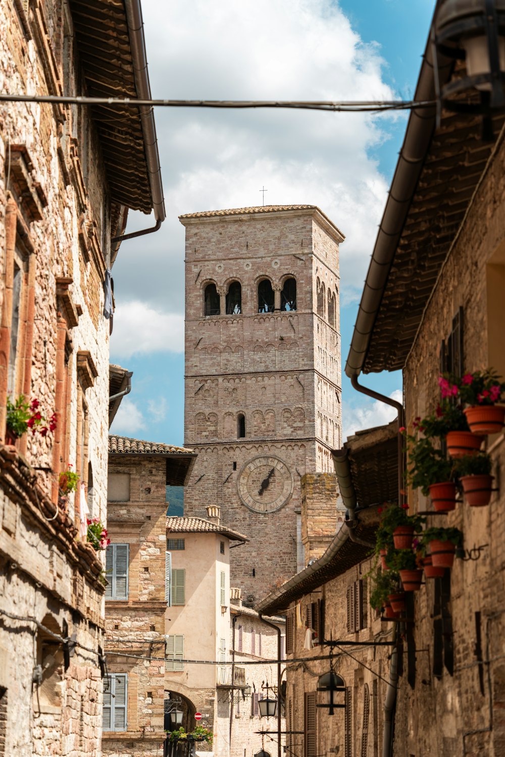 Una strada stretta con una torre dell'orologio sullo sfondo