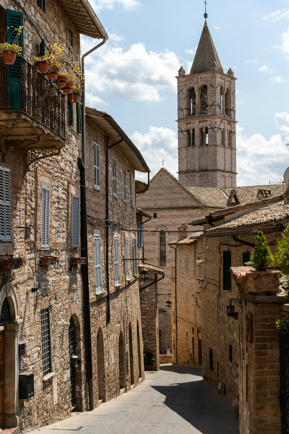 a narrow street with a church steeple in the background