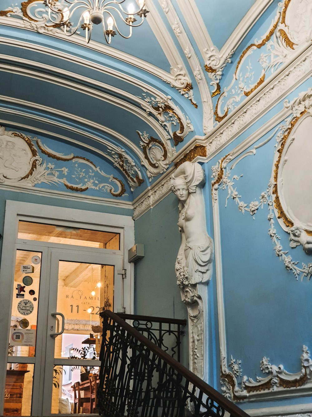 a blue and white room with a stair case and chandelier