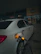 Man happily filling his car at a gas station with a fuel saver device visible.
