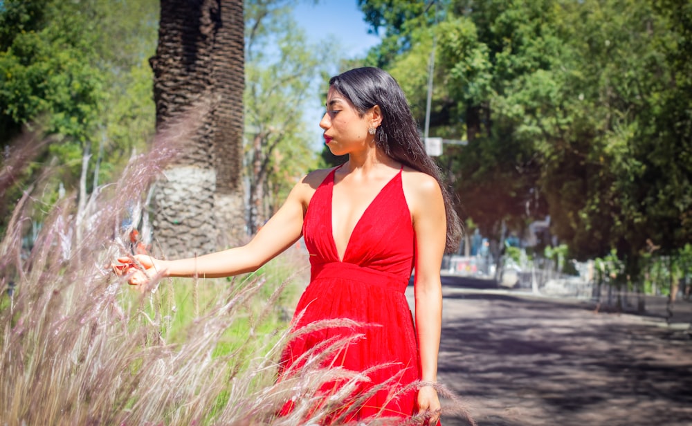 a woman in a red dress is walking through tall grass