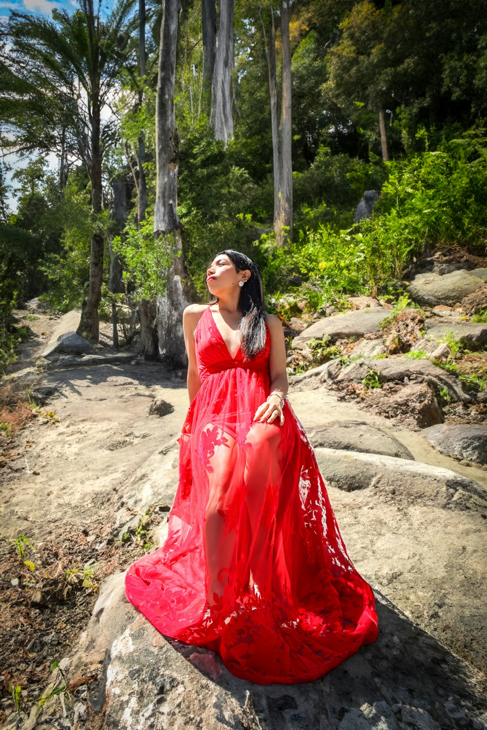 a woman in a red dress sitting on a rock