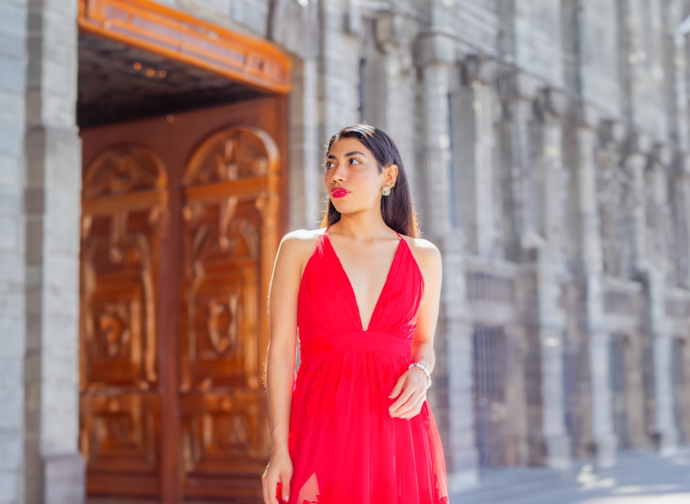 a woman in a red dress standing in front of a building