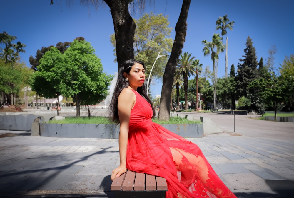 a woman in a red dress sitting on a bench