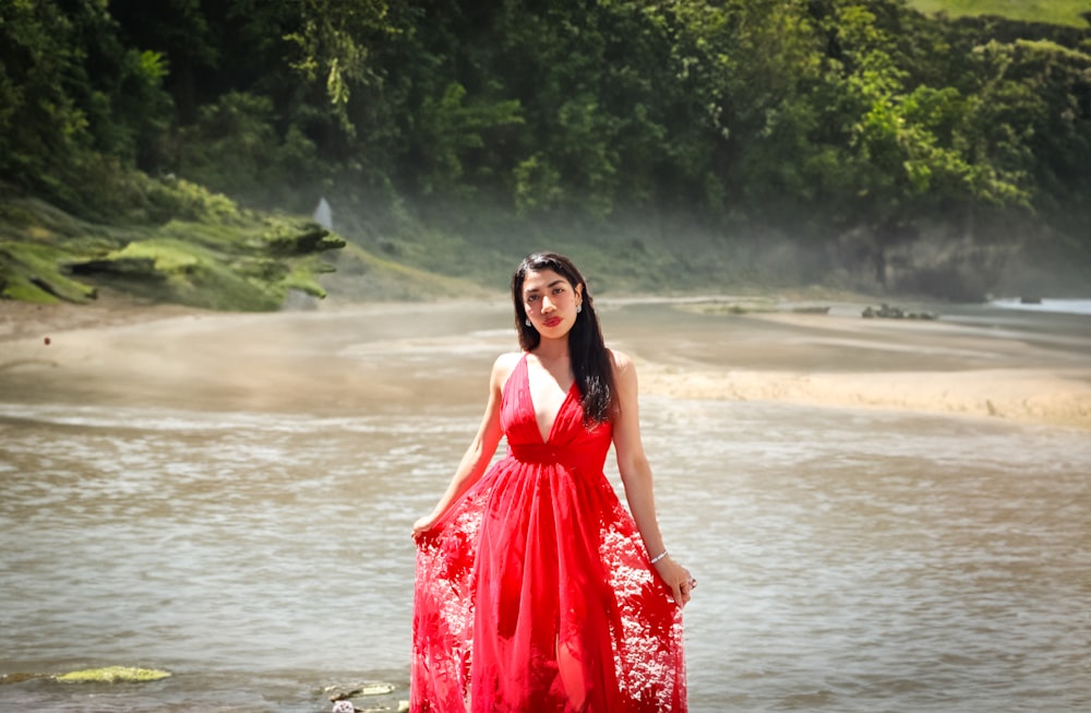 a woman in a red dress standing on a beach