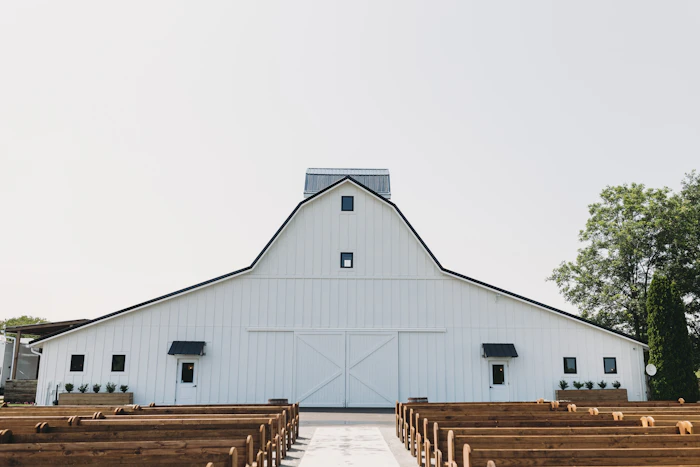 A large white barn interior with rows of wooden pews
