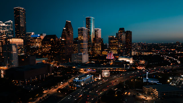 Illuminated downtown Houston towers and the Downtown Aquarium Ferris wheel at dusk