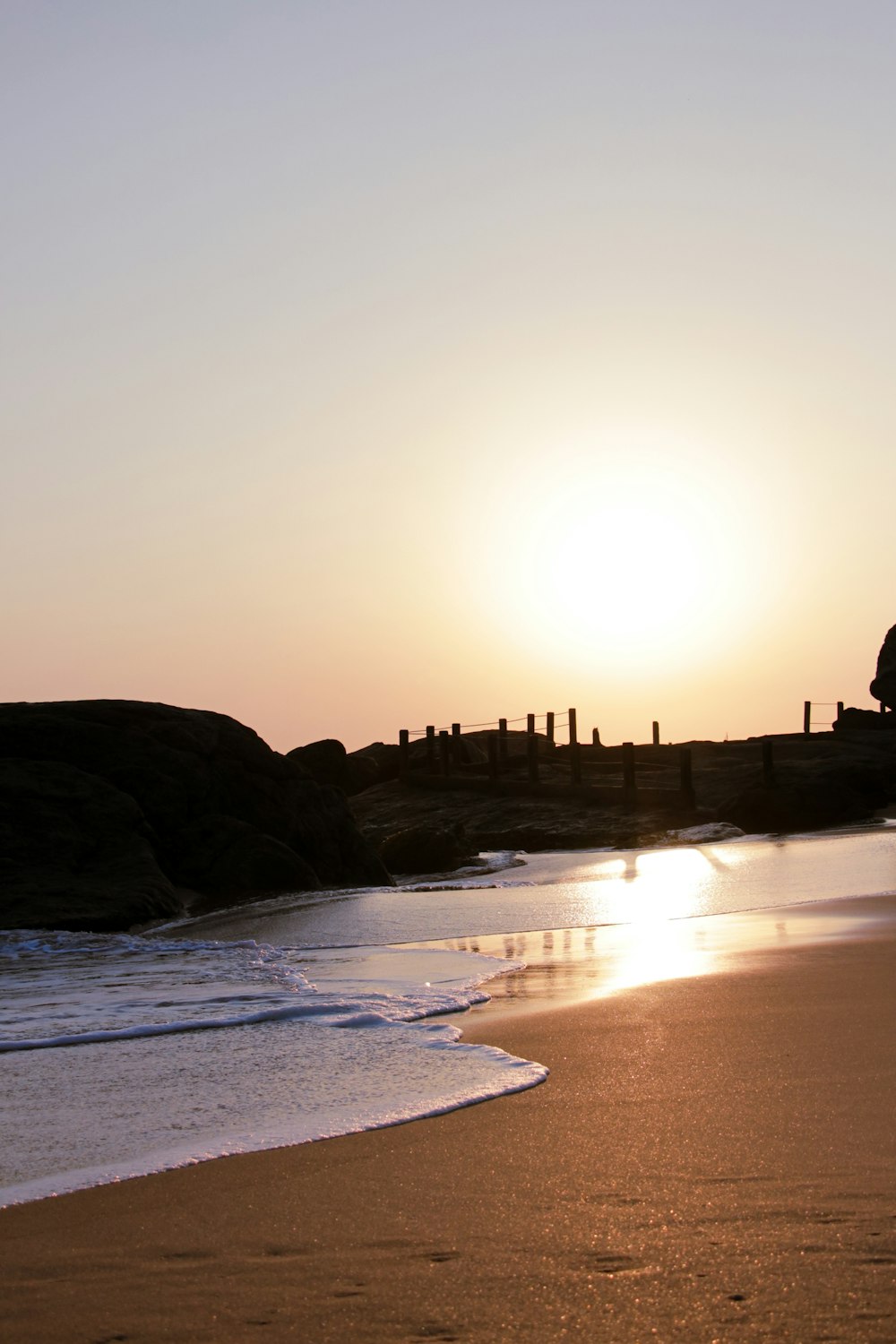 the sun is setting over the water at the beach