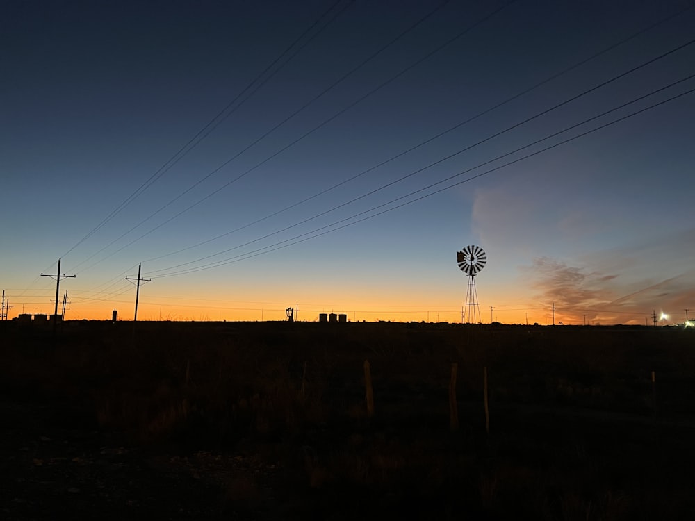 a windmill in the distance with power lines in the foreground