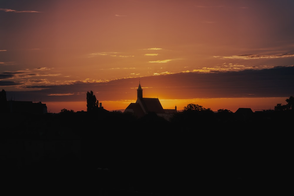 the sun is setting behind a church tower