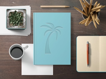 Close-up of elegant notebooks and planners stacked on a clean desk with a cup of coffee nearby.