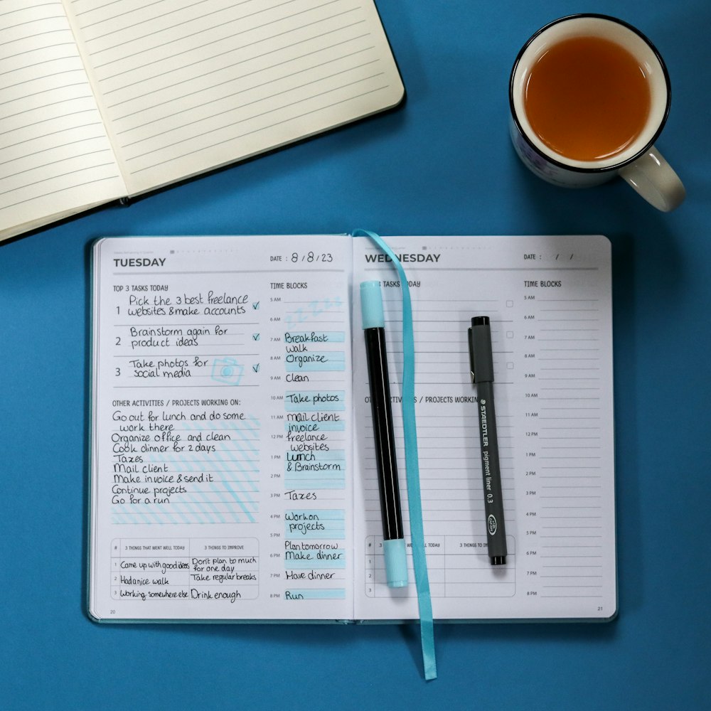 a notebook with a pen and a cup of tea