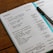 An open planner displaying a detailed schedule for Tuesday and Wednesday, including tasks such as creating freelance accounts and organizing activities. A pen is placed on the planner, and the pages are filled with handwritten notes outlining tasks, time blocks, and projects.