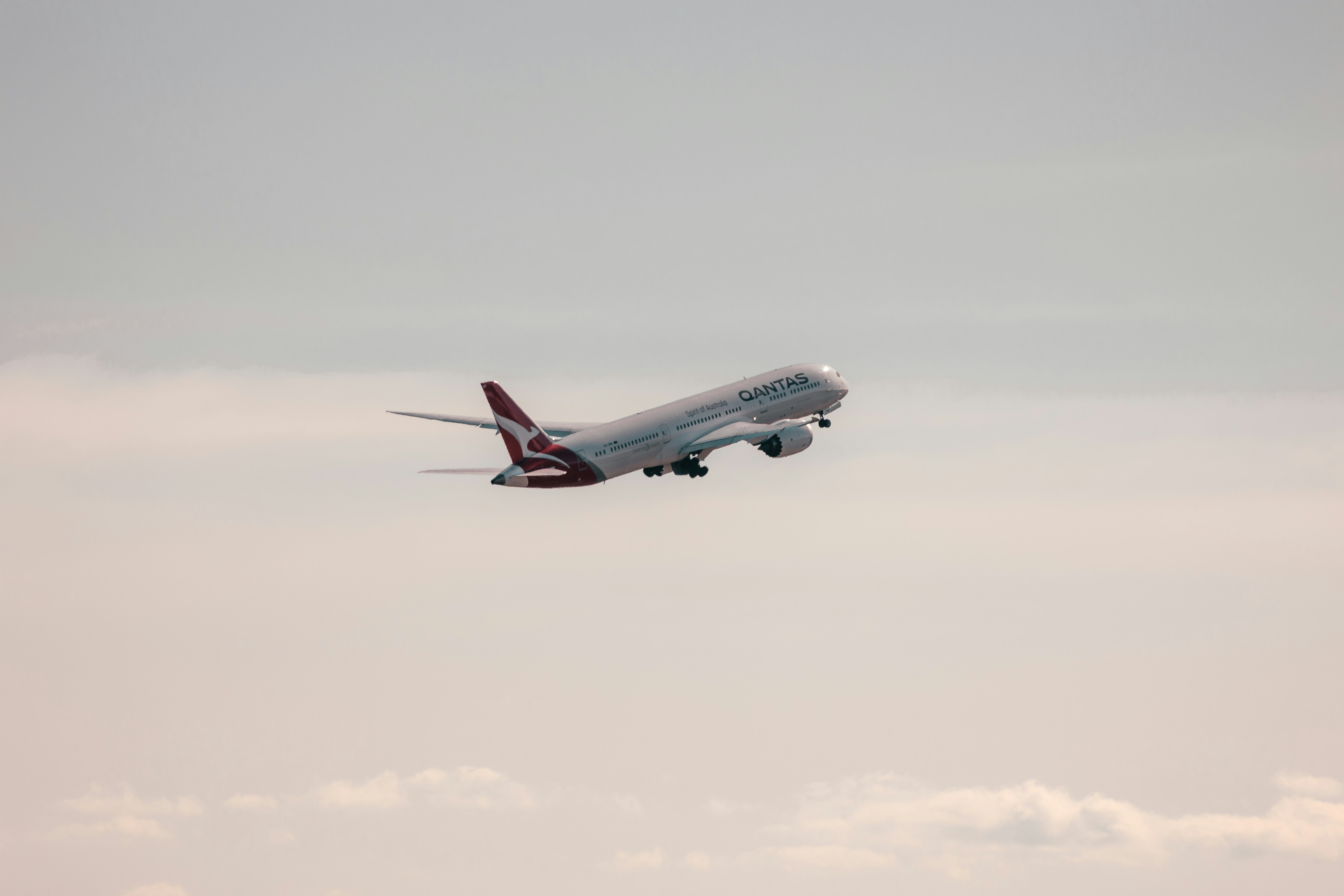 a large jetliner flying through a cloudy sky, Qantas - Boeing 787 Dreamliner - VH-ZNH