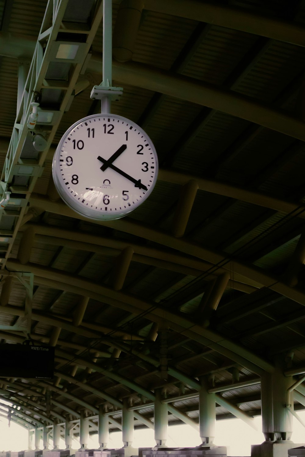 a clock hanging from the ceiling of a train station