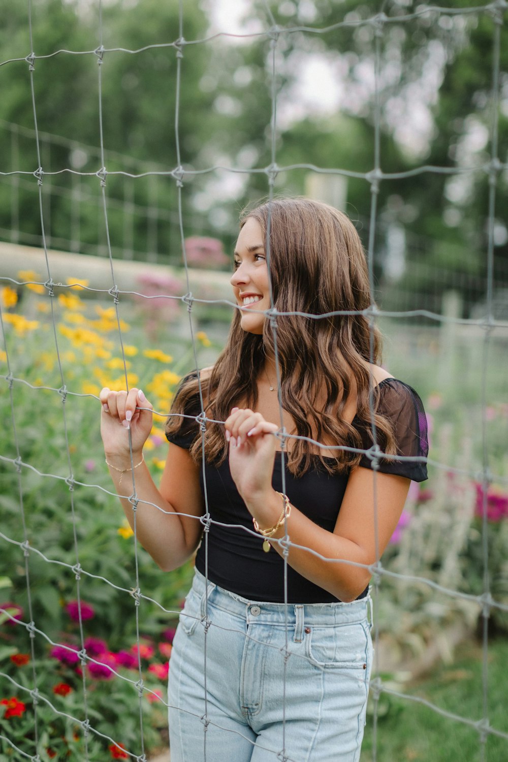 a woman standing behind a fence in a garden