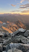 Controlled blasting operation in a rocky mountainous terrain at sunset.