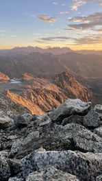 Controlled blasting operation in a rugged mountainous terrain at sunset.