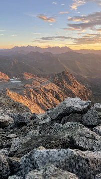 Controlled blasting operation in a rugged mountainous terrain at sunset.