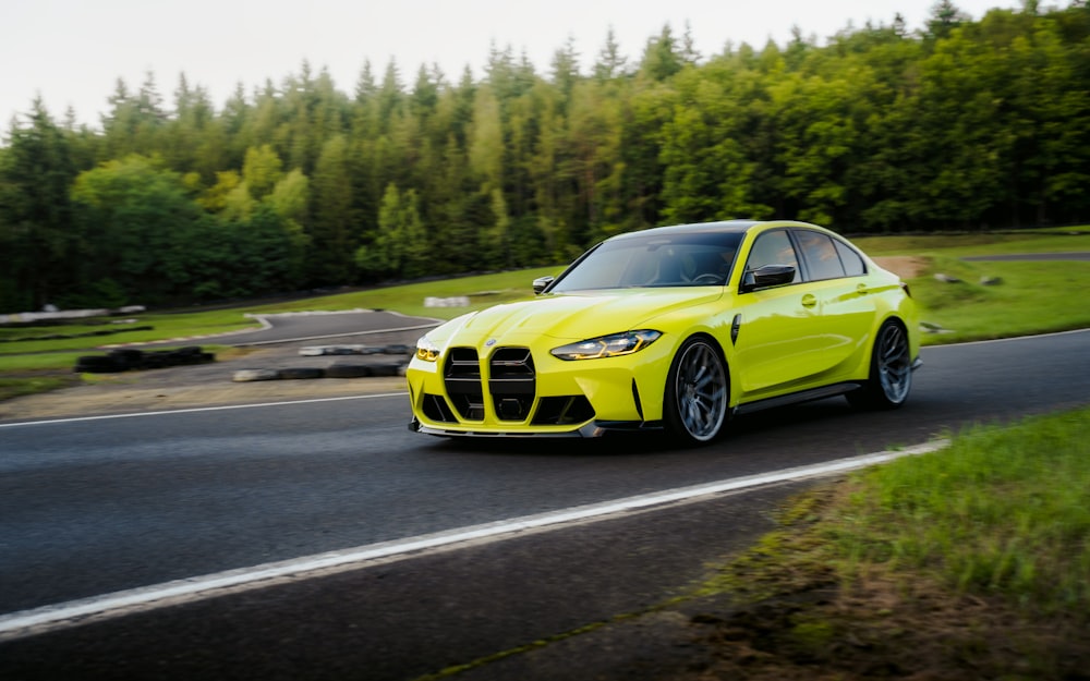 a yellow car driving down a road next to a forest