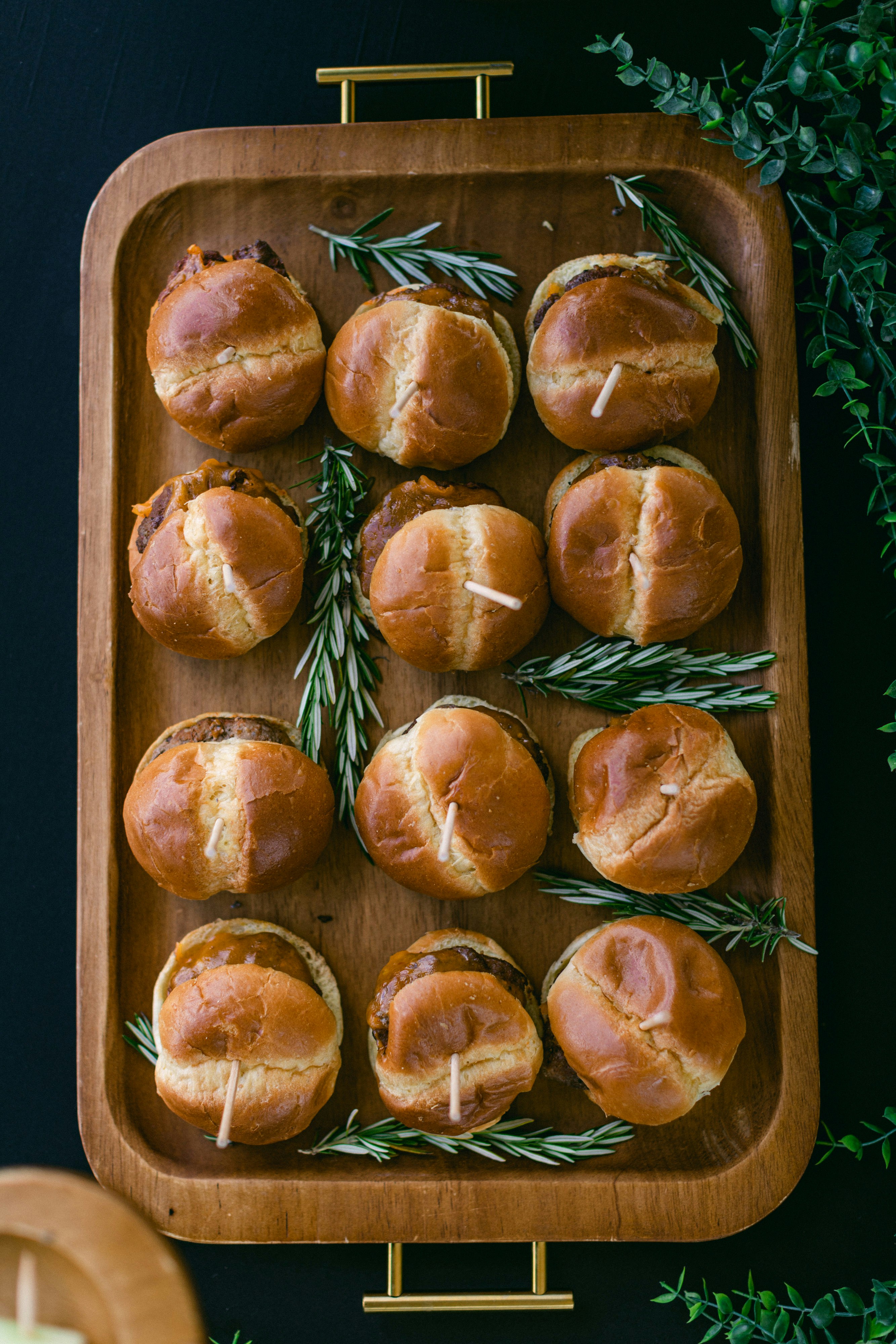 Mini sliders with fresh toppings on wooden board, bright food photography