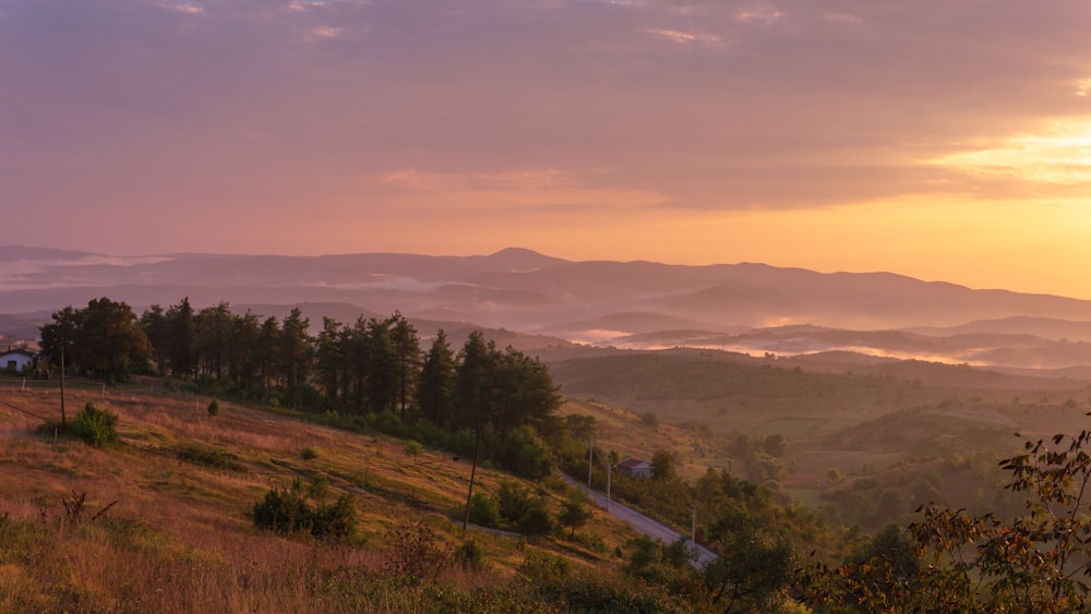 the sun is setting over the mountains and valleys