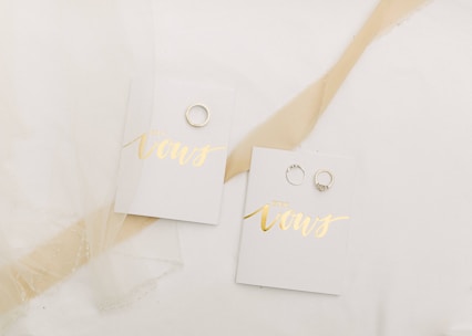 Close-up of a beautifully decorated wedding vow booklet with elegant calligraphy on a white lace tablecloth.