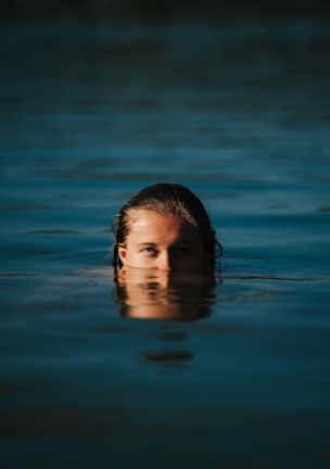 Close-up of a diver’s calm face framed by the rippling water surface above.