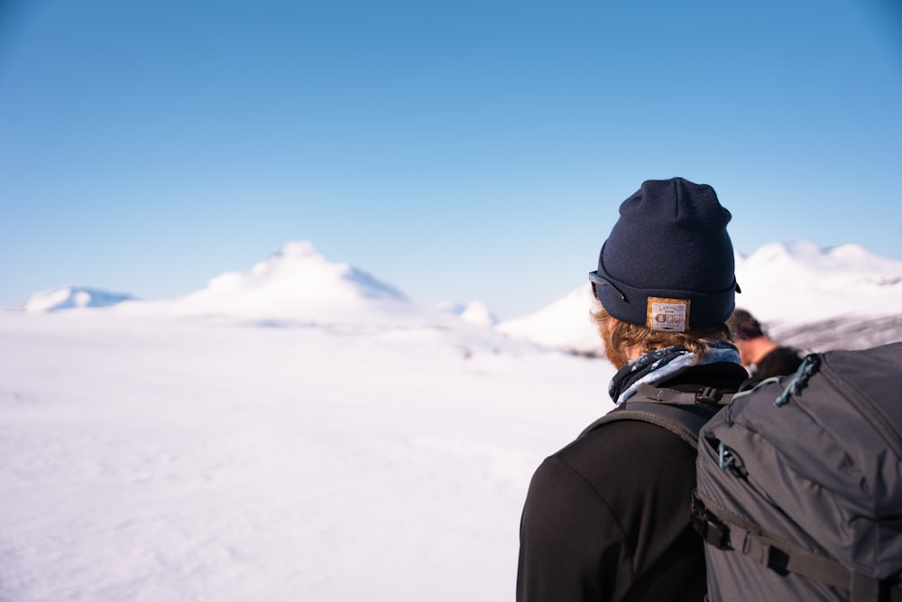 une personne debout dans la neige avec un sac à dos