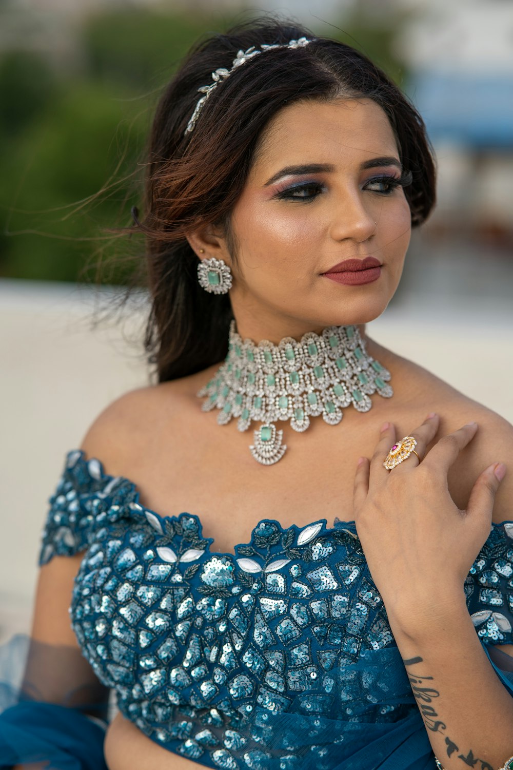 a woman in a blue dress wearing a necklace and earrings