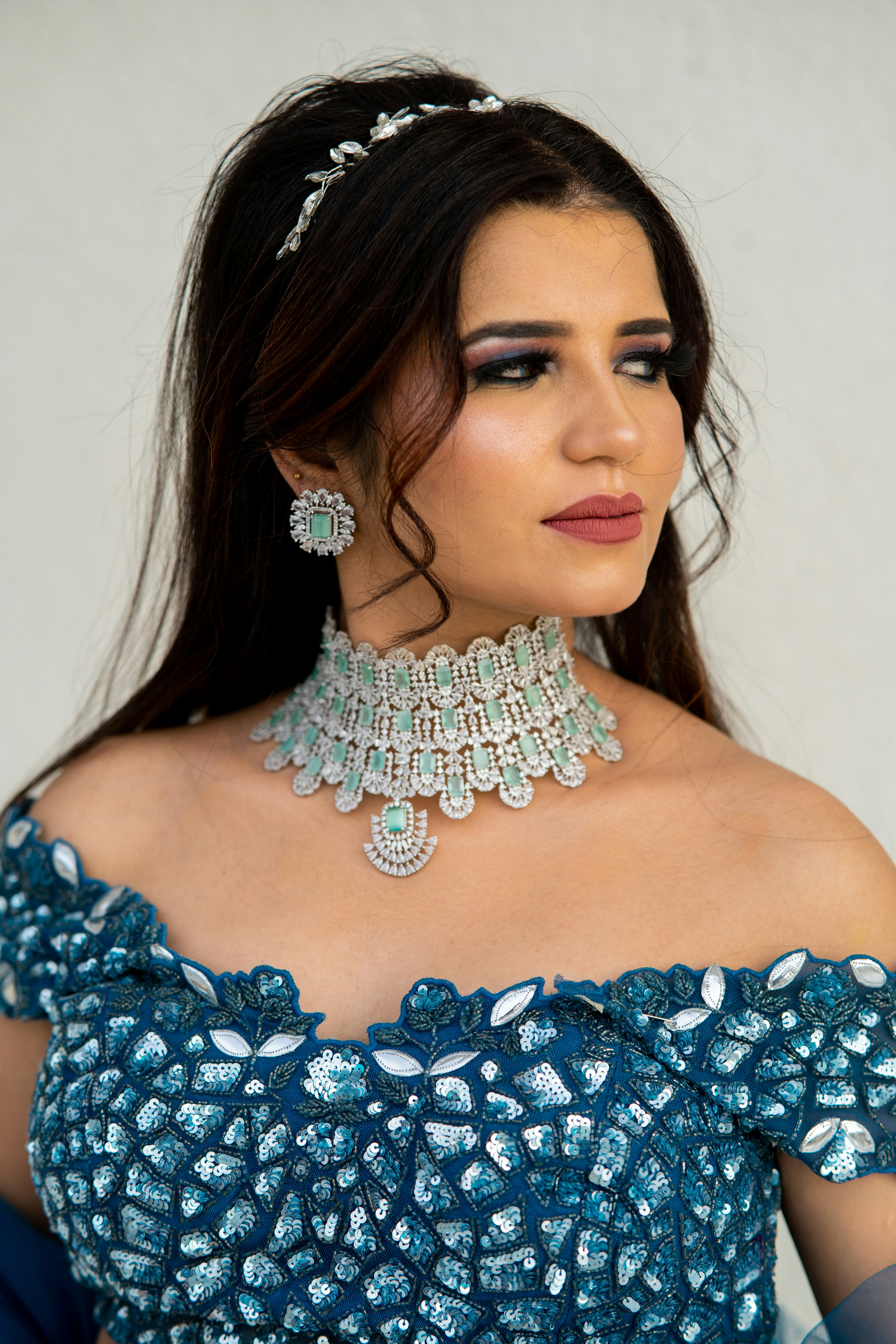 A woman in a blue dress with a necklace and earrings photo – Free ...