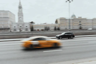 Yellow geometric shapes overlaying a dynamic shot of a car speeding on a city street