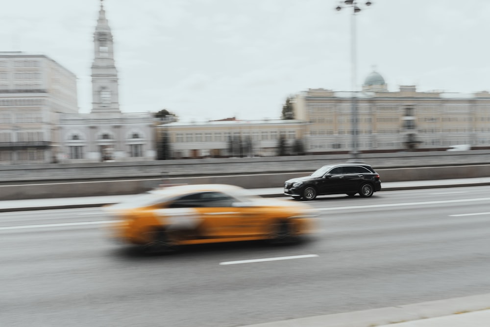 a black car and a yellow car driving down a street