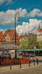 A charming European street with cobblestone pavement and colorful historic buildings under a bright sky.