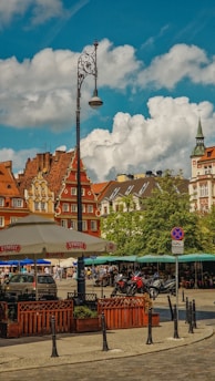 A charming European street with cobblestone pavement and colorful historic buildings under a bright sky.