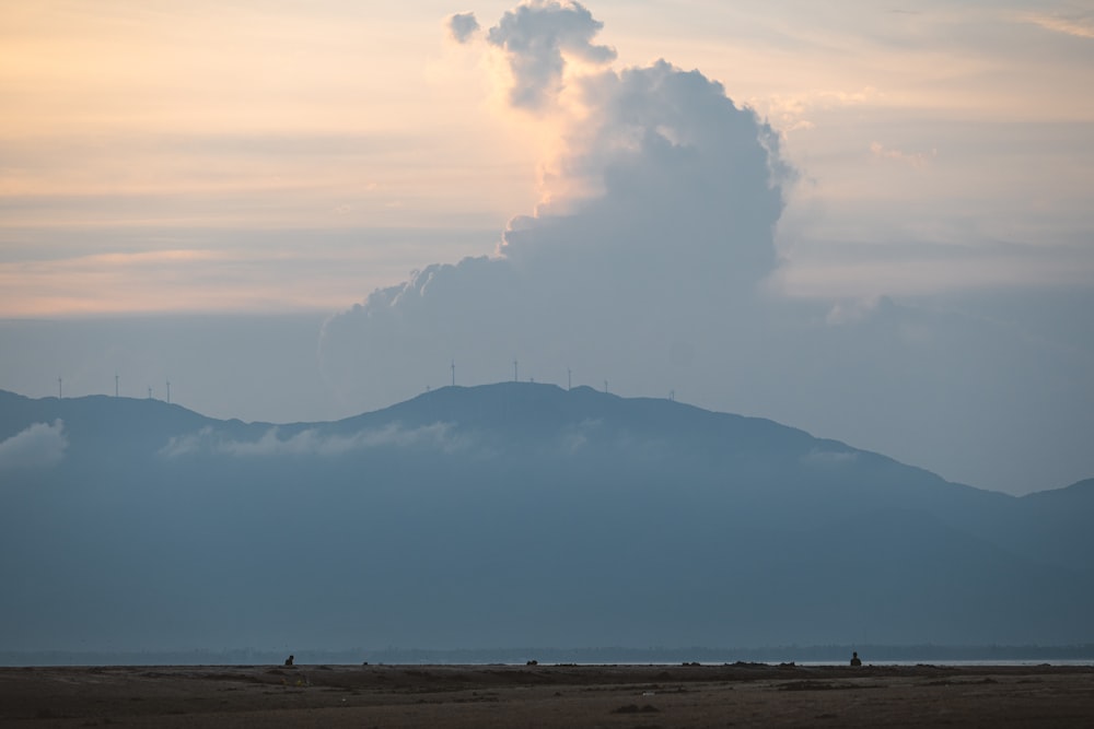 a large cloud is in the sky over a mountain