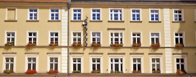 Facade of a yellow townhouse with flower boxes on the windows